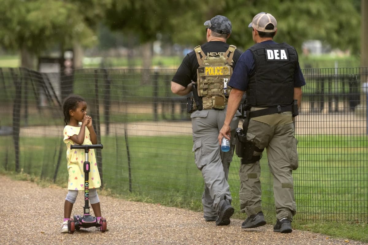 Una niña observa mientras agentes de la Administración para el Control de Drogas patrullan a lo largo del National Mall el miércoles 13 de agosto de 2025, en Washington. | Crédito: AP/Mark Schiefelbein