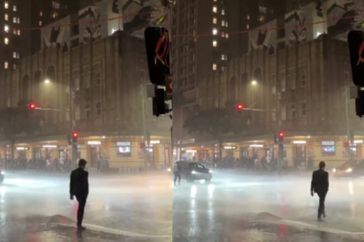 Hombre es captado caminando bajo la lluvia en traje, como si estuviera en una pasarela