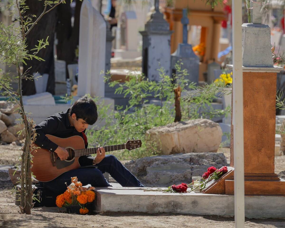 Un joven toca la guitarra frente a una de las tumbas del panteón municipal en Mexicali, este Día de Muertos. (Foto: Javier Gallegos)