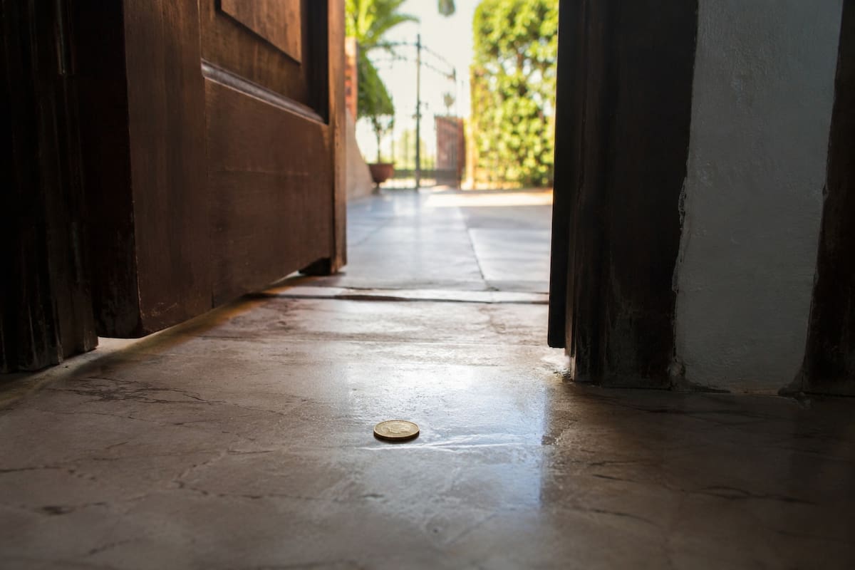 Moneda encontrada en la puerta de una casa como símbolo de prosperidad según creencias populares. | Imagen hecha con IA de ChatGPT