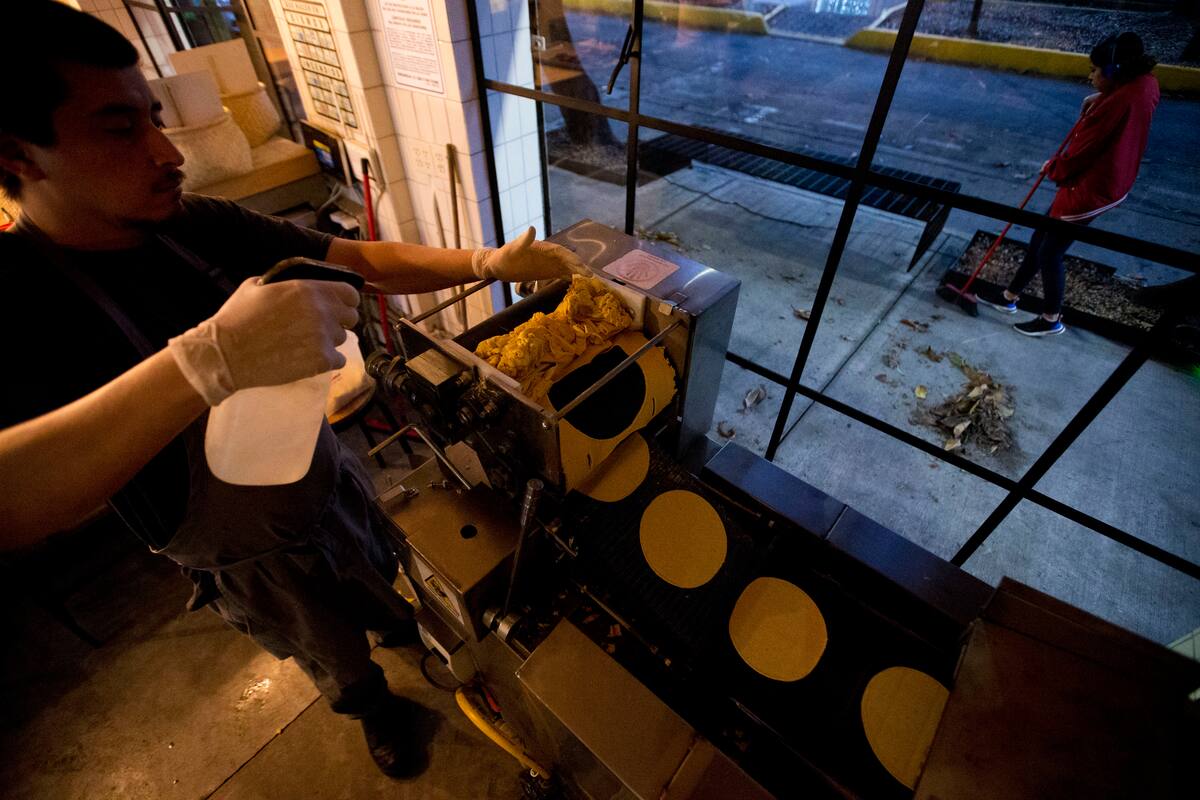 El chef Jesús Saldívar coloca maíz molido a través de la máquina para hacer tortillas en el molino de El Pujol en el barrio de Condesa de la Ciudad de México, el martes 9 de abril de 2019. (AP Foto / Rebecca Blackwell)
