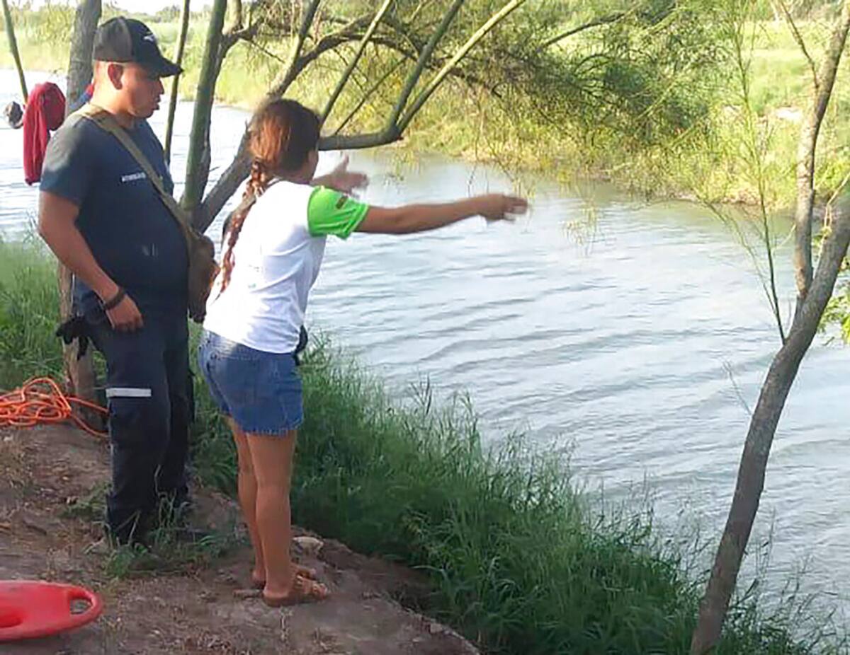 En esta imagen del domingo 23 de junio de 2019, Tania Vanessa Ávalos, de El Salvador, habla con las autoridades mexicanas después de que su esposo y su hija, de casi dos años de edad, fueran arrastrados por la corriente mientras intentaban cruzar el Río Bravo desde Matamoros, México, hacia Brownsville, Texas. (AP Foto/Julia Le Duc)