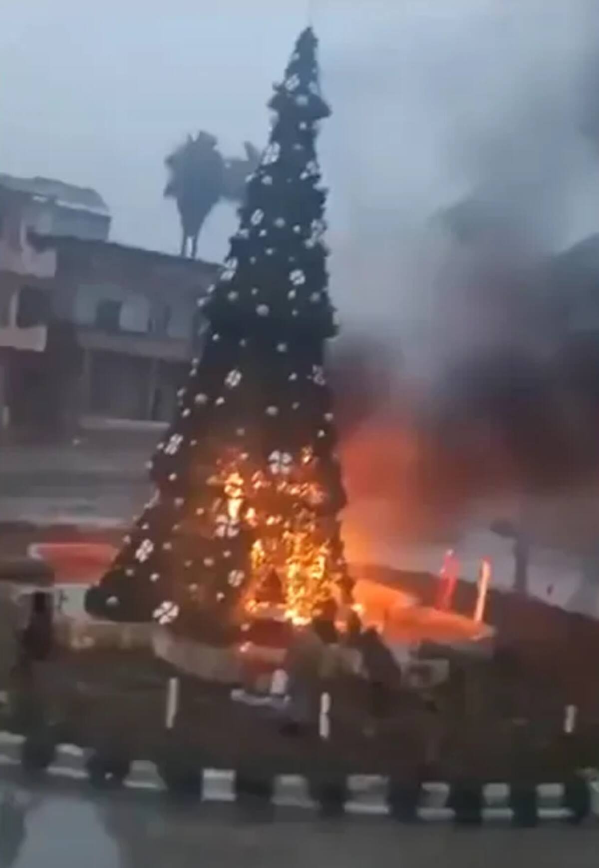 Una imagen tomada de un video en el que se observa a hombres incendiando un árbol de Navidad exhibido en un espacio público en la ciudad de Suqaylabiyah, predominantemente cristiana, situada cerca de Hama. / CNN.