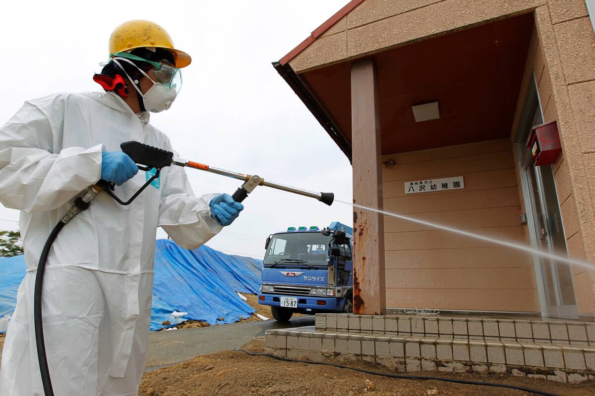 A worker decontaminates radiation from the exterior of Yasawa Kindergarten in Minami-Soma, about 12 miles (20 kilometers) away from the tsunami-crippled Fukushima Dai-ichi nuclear facility, in Fukushima prefecture, northeastern Japan, Thursday, Aug. 18, 2011. Feeling forgotten and left largely to fend for themselves by the central government, officials in the half-empty city on the edge of the evacuation zone have designated August as "Decontamination Month" in a campaign to woo spooked residents home. (AP Photo/Hiro Komae)