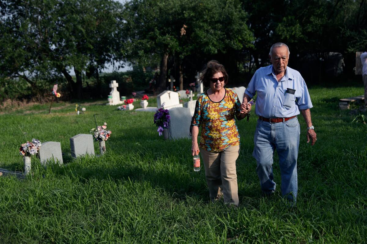 Oliverio Yarrito, de 80 años, y su esposa Odilita, de 79, caminan por el Cementerio Eli Jackson de San Juan, Texas, donde está enterrado el padre de Oliverio el 1ro de mayo del 2019. El cementerio se encuentra en una zona de la frontera con México donde el gobierno estadounidense quiere construir un muro. (AP Photo/Eric Gay)