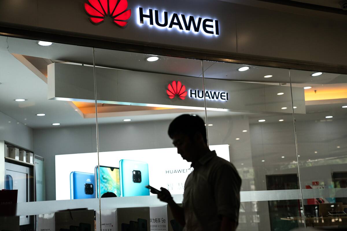 A man walks past a Huawei logo displayed at a retail store in Beijing on May 23, 2019. - Chinese telecom giant Huawei says it could roll out its own operating system for smartphones and laptops in China by the autumn after the United States blacklisted the company, a report said on May 23. (Photo by FRED DUFOUR / AFP)