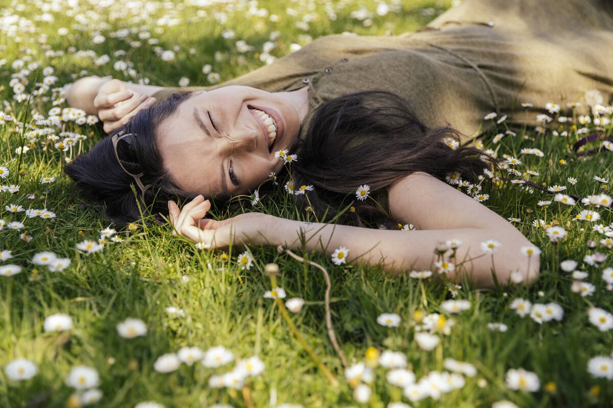 Woman enjoying her free time while laying on grass with many daisies, Cologne, NRW, Germany