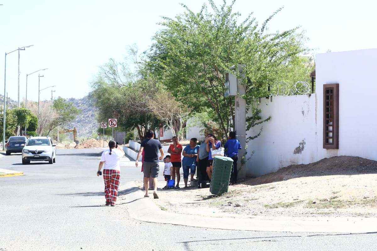 Vecinos se mojan con agua de manguera para soportar el calor mientras esperan que regrese la energía eléctrica.