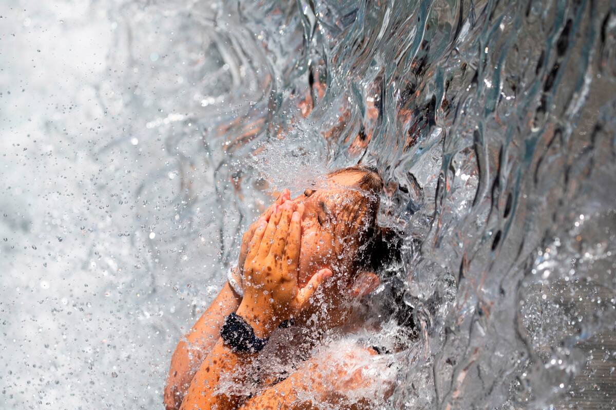 Una persona se refresca en una cascada de agua. EFE/EPA/MICHAEL REYNOLDS