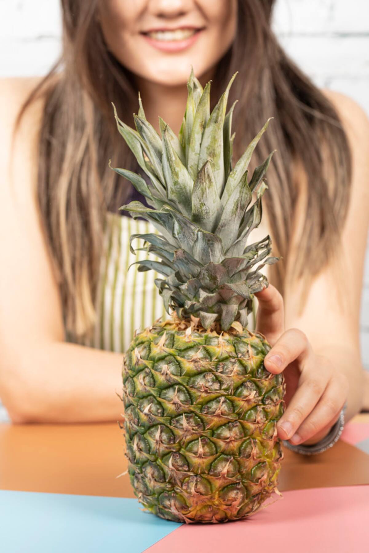 Woman putting a pineapple on the table. High quality photo