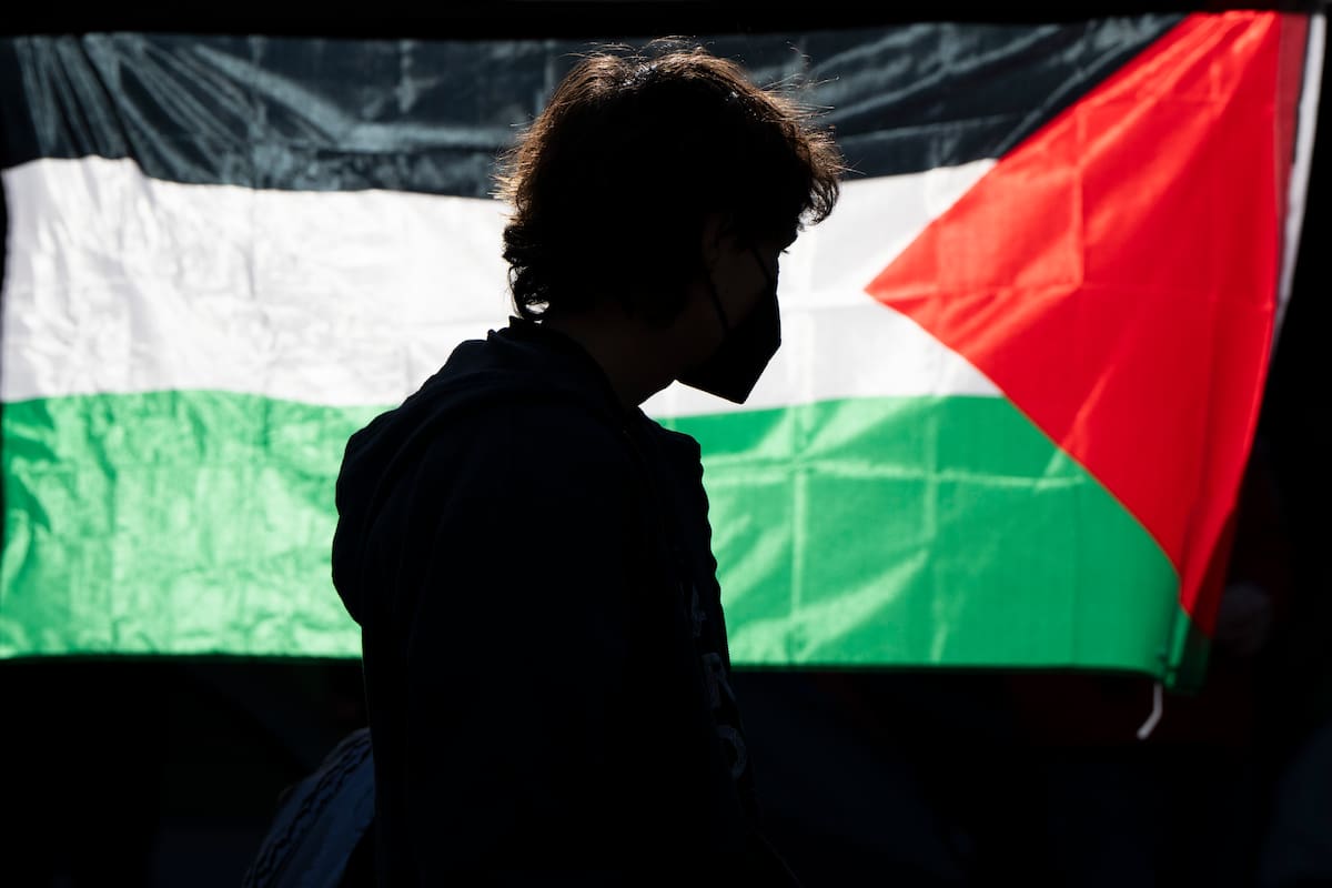 La silueta de un alumno de la Universidad de Oregon se ve ante una bandera palestina en un campamento de carpas levantado en la universidad como protesta por la guerra entre Hamás e Israel, el 29 de abril de 2024 en Eugene, Oregon. (AP Foto/Jenny Kane)