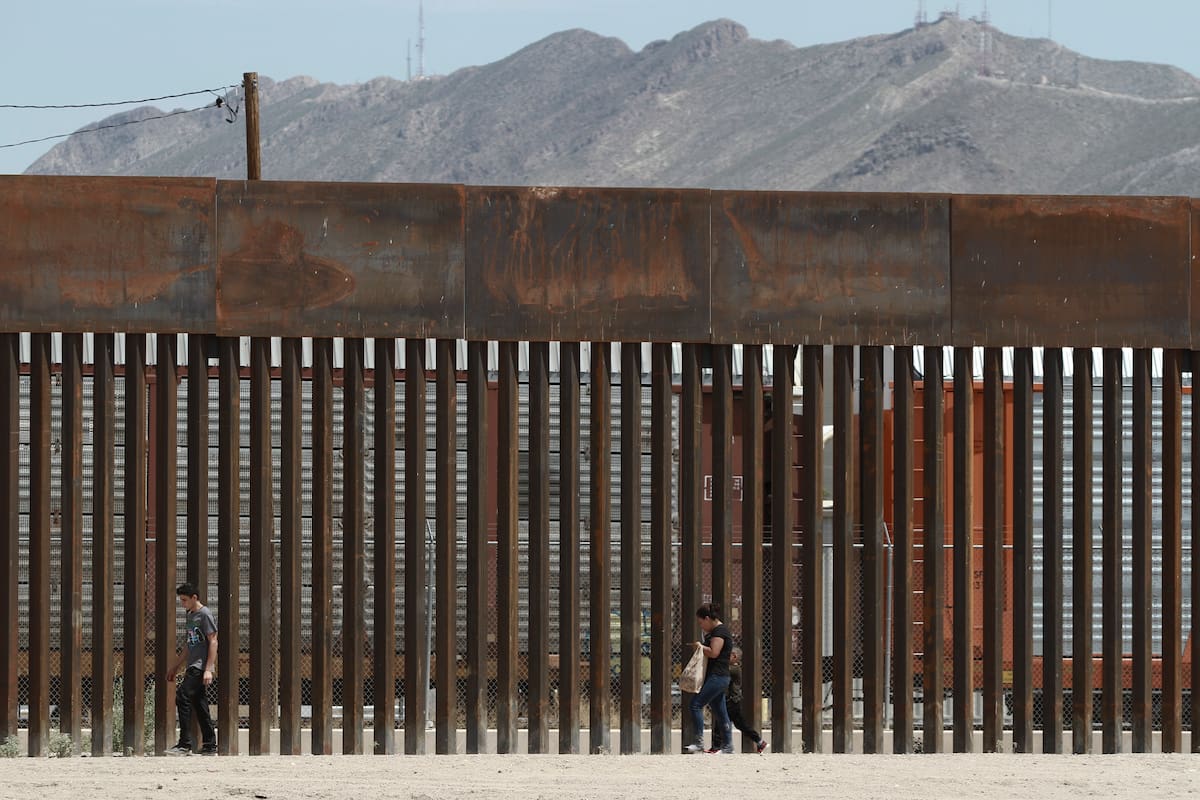 ARCHIVO - En esta foto del 17 de julio del 2019, tres migrantes que evadieron a la Guardia Nacional de México y cruzaron el Río Grande hacia Estados Unidos caminan junto a una barrera fronteriza instalada cerca de la frontera geográfica en El Paso, Texas. (AP Foto/Christian Chávez)