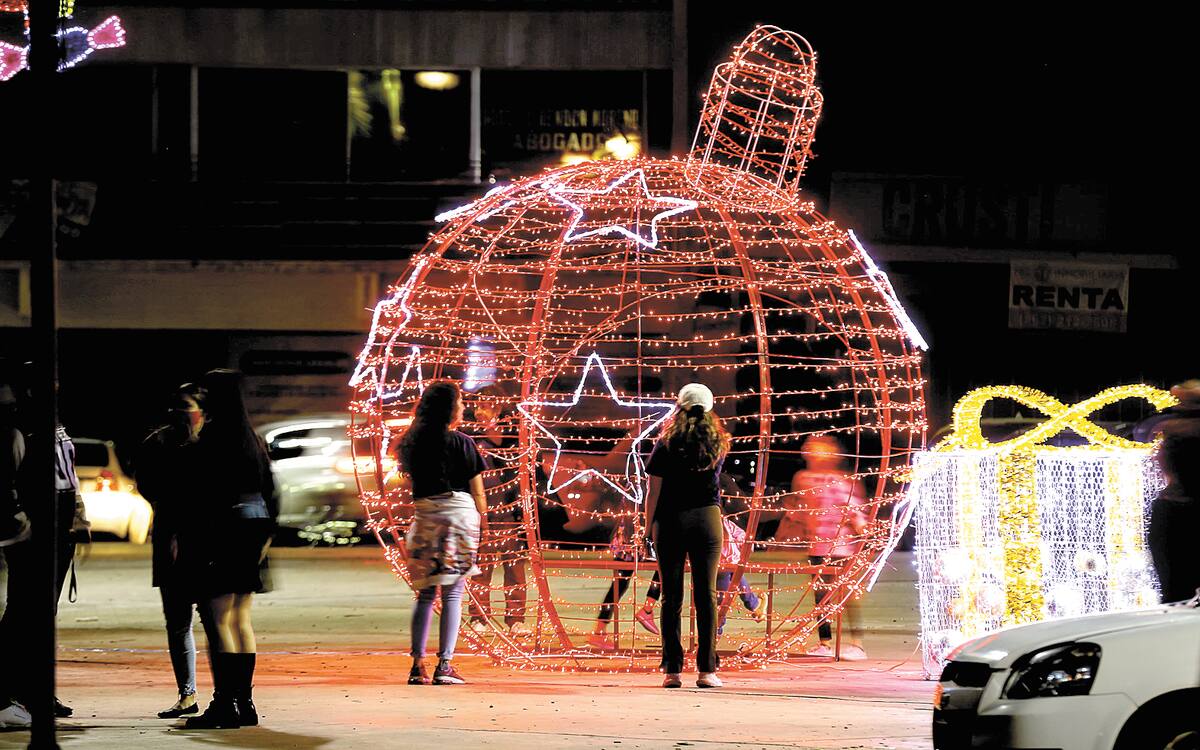 Hermosillenses admiran una esfera gigante que forma parte de la decoración navideña en el Centro Cívico de Hermosillo.