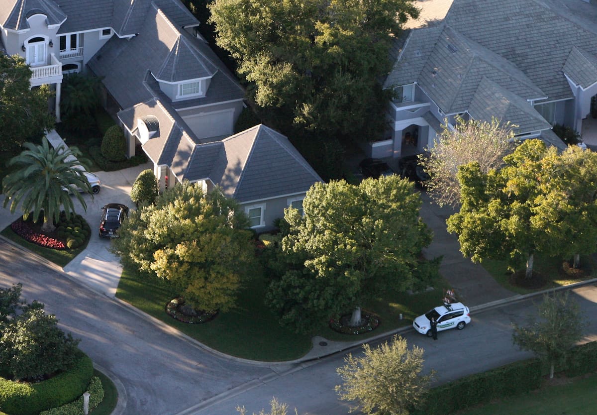 Un agente de seguridad custodia el área frente a la casa de Tiger Woods, a la izquierda, en Windermere, Florida, el viernes 27 de noviembre de 2009. Woods resultó herido en un accidente ocurrido la madrugada del viernes, cuando su vehículo utilitario deportivo chocó contra un hidrante y un árbol cerca de su mansión, ubicada en una comunidad privada frente al agua. (Foto AP/Orlando Sentinel, Gary W. Green)
