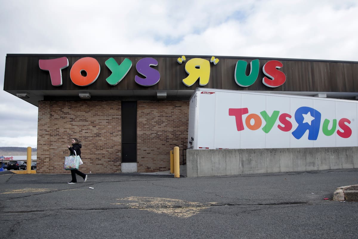 A woman walks near the loading dock of a Toys R Us store, Wednesday, Jan. 24, 2018, in Wayne, N.J. Toys R Us, squeezed by Amazon.com and huge chains like Walmart, will close 180 stores, including this location at the Wayne Hills Mall, within months. At some other locations, the retailer is combining its Toys R Us and Babies R Us stores. Toys R Us operates about 900 stores in the U.S. (AP Photo/Julio Cortez)