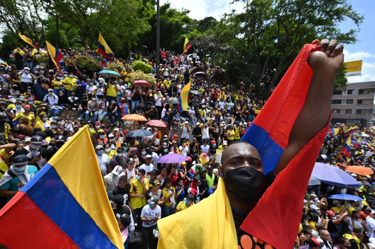 People hold a sign reading Democracy is not in quarantine during protest against a tax reform bill they say will leave them poorer as the country battles its deadliest phase yet of the coronavirus pandemic, in Cali, Colombia, on May 1, 2021. - Colombian President Ivan Duque caved in on April 30 to widespread anger and said he would overhaul the proposed tax reform. Duque announced he was shelving clauses that would lower the income tax threshold to broaden the tax base and raise value-added taxes on goods and services. (Photo by Luis ROBAYO / AFP) (Photo by LUIS ROBAYO/AFP via Getty Images)