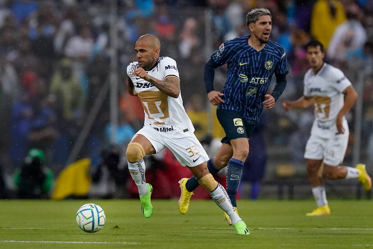 El brasileño Dani Alves de Pumas UNAM avanza con el el balón junto a Diego Valdés del América, en un encuentro de la Liga MX, disputado el sábado 13 de agosto de 2022 (AP Foto/Eduardo Verdugo)