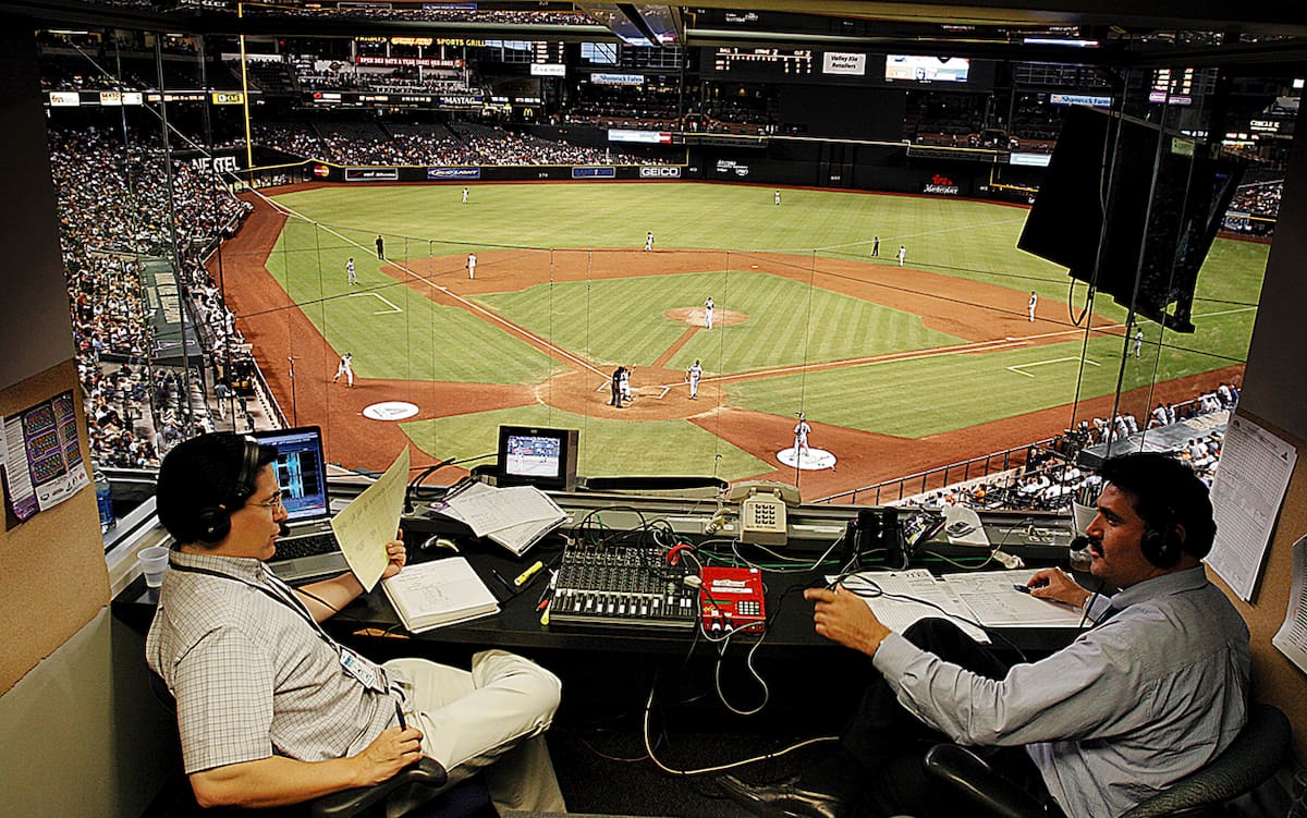 Óscar Soria y Miguel Quintana hacen sus comentarios durante un juego entre los Diamondbacks de Arizona y los New York Mets en el Bank One Ballpark de Phoenix, en 2005.