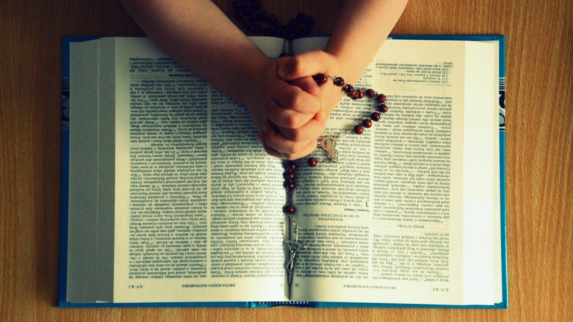 Niño rezando sobre una biblia. Foto: Ilustrativa/Canva