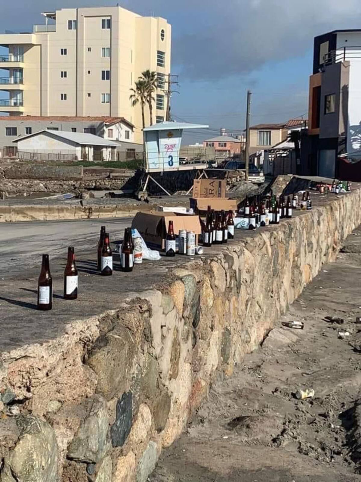 Decenas de botellas vacías fueron abandonadas en la barda de la playa.