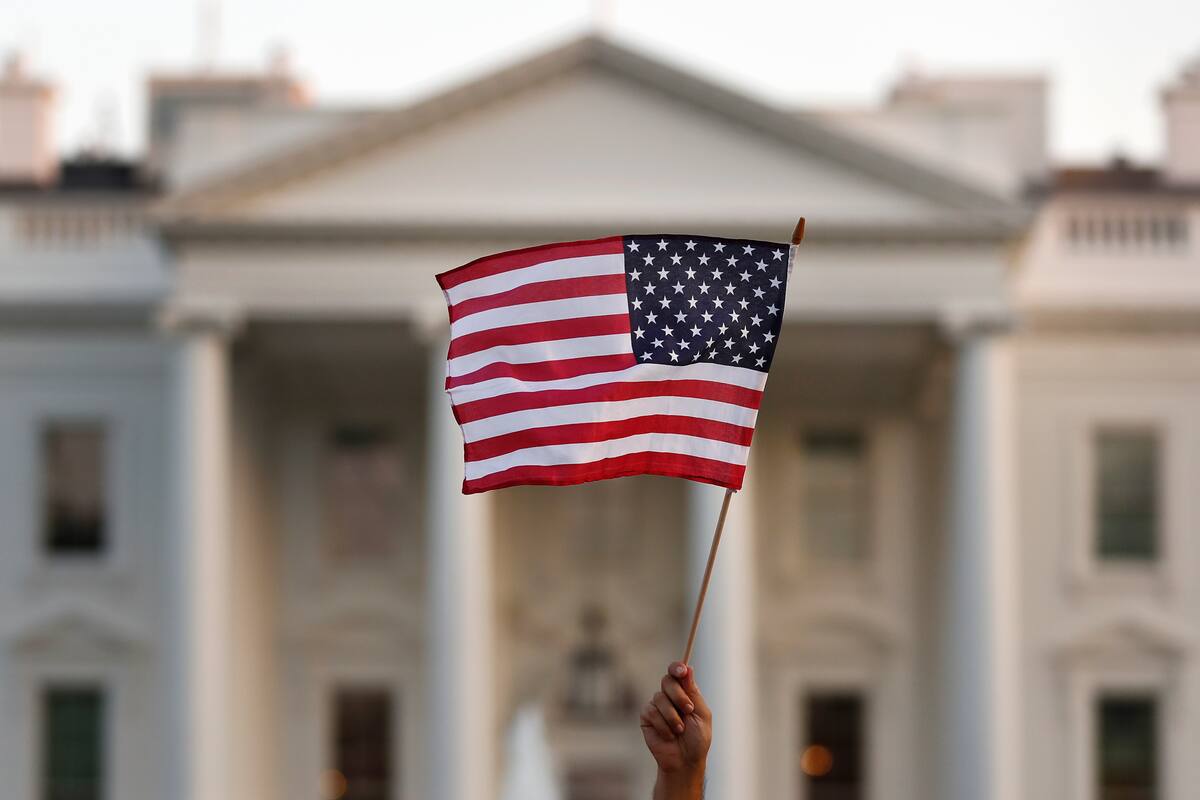 FILE - In this Sept. 2017 file photo, a flag is waved during an immigration rally outside the White House, in Washington. President Donald Trump has touted the creation of an office created to help victims of crimes committed by people in the U.S. illegally. But most of the people calling the Trump administration hotline aren’t calling to get information. They are calling to report their neighbors, colleagues or strangers who they suspect are in the country illegally. (AP Photo/Carolyn Kaster)