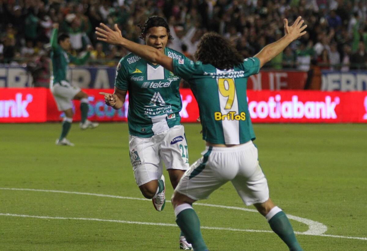 Leon's Carlos Pena, left, celebrates with his teammate Matias Britos after scoring against America during the Mexico league first leg soccer final match in Leon, Mexico, Thursday, Dec. 12, 2013 (AP Photo/Mario Armas)
