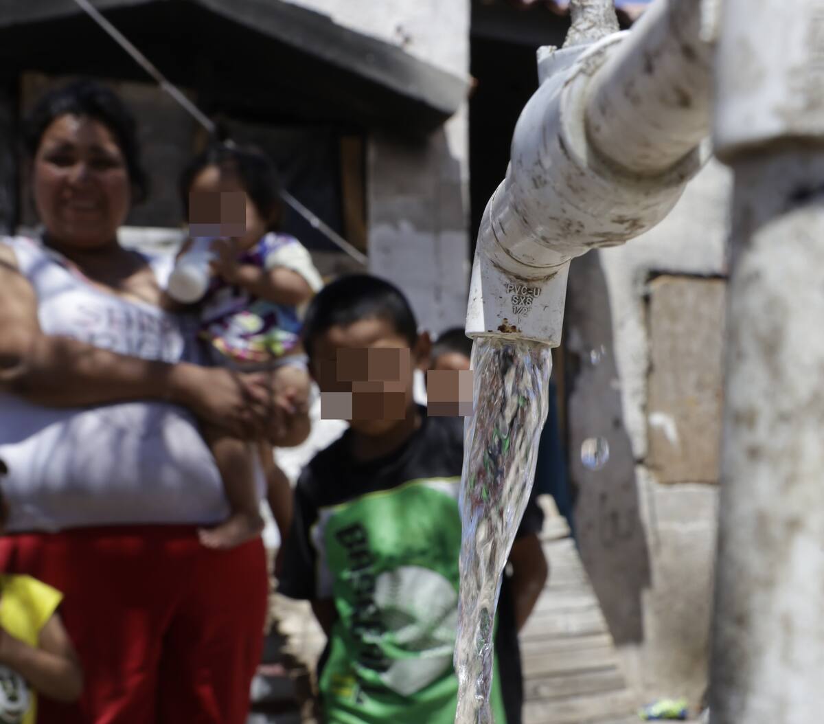 Bajo este chorrito de agua seis niños de 10, 9, 7, 6, 4 y 1 año de edad, mitigan el calor y se sientan bajo la sombra de un árbol, pues adentro de la vivienda es imposible estar, en la colonia Villa Verde. FOTO: TEODORO BORBÓN