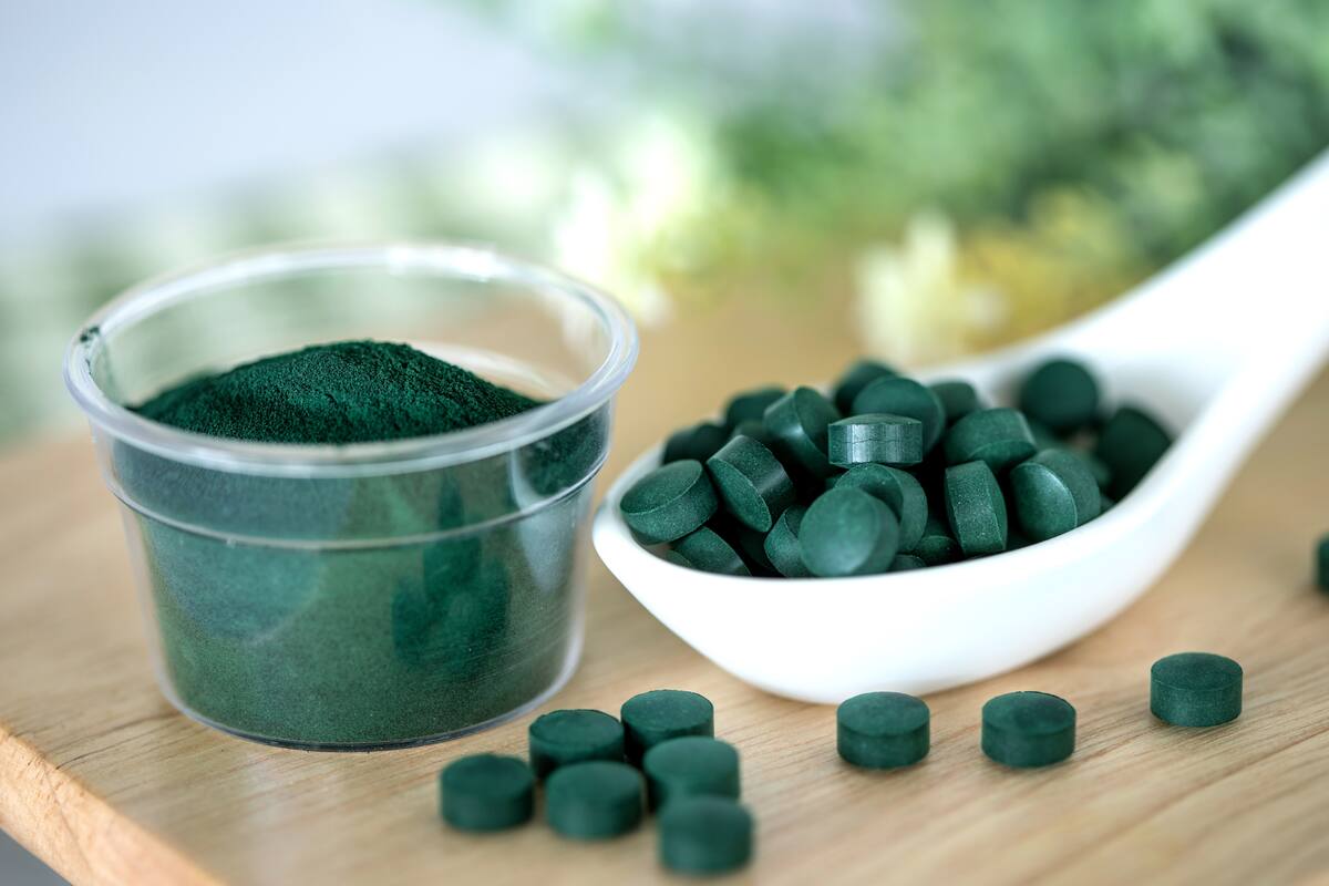 Close up a spirulina powder and spirulina pills in spoon , healthy superfood diet and detox nutrition concept