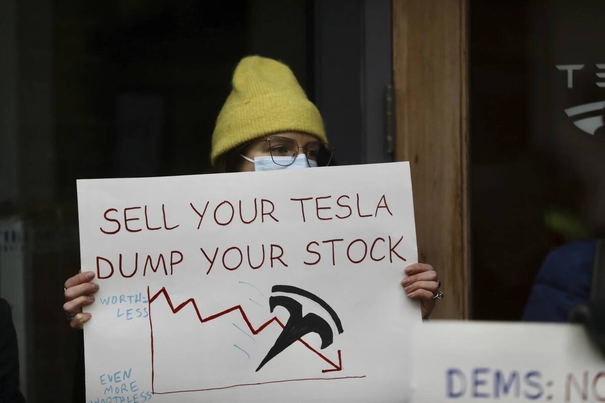 Una persona que protesta contra las acciones de Elon Musk en la administración de Trump sostiene un cartel fuera de una sala de exhibición de Tesla en Seattle el jueves 13 de febrero de 2025. | Crédito: AP/Manuel Valdes, archivo