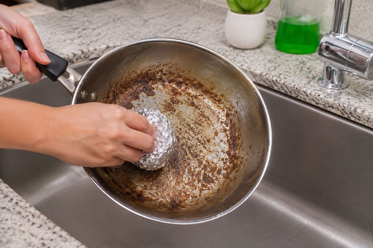 Si forma una bola con el papel y añade un poco de detergente, podrá frotar sartenes o superficies metálicas con grasa pegada | Imagen hecha con IA