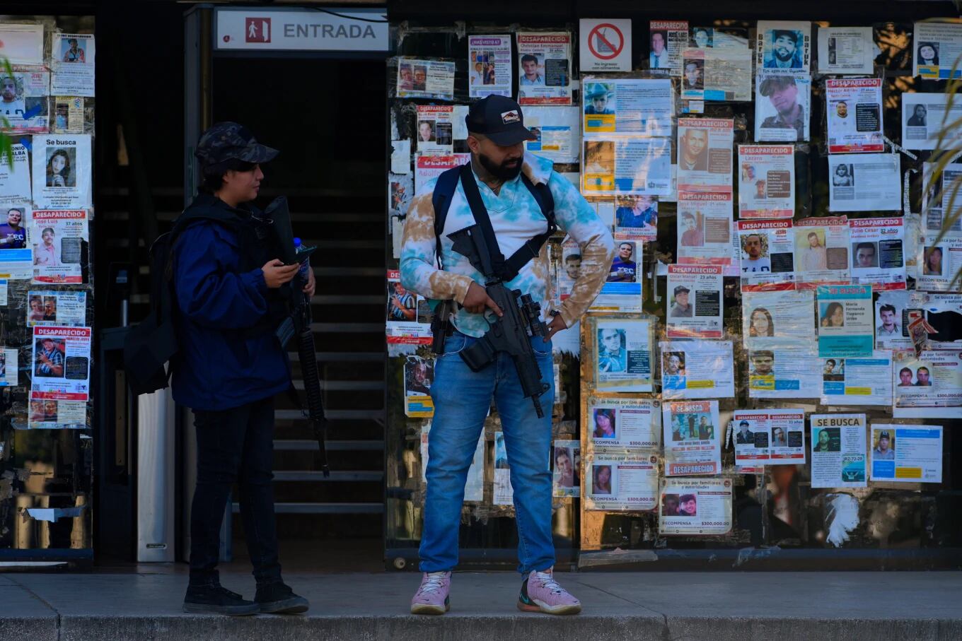Agentes de policía junto a carteles de personas desaparecidas frente a la Fiscalía Especializada para la Atención de Personas Desaparecidas en Guadalajara, México, el miércoles 25 de febrero de 2026. (Foto AP/Marco Ugarte)