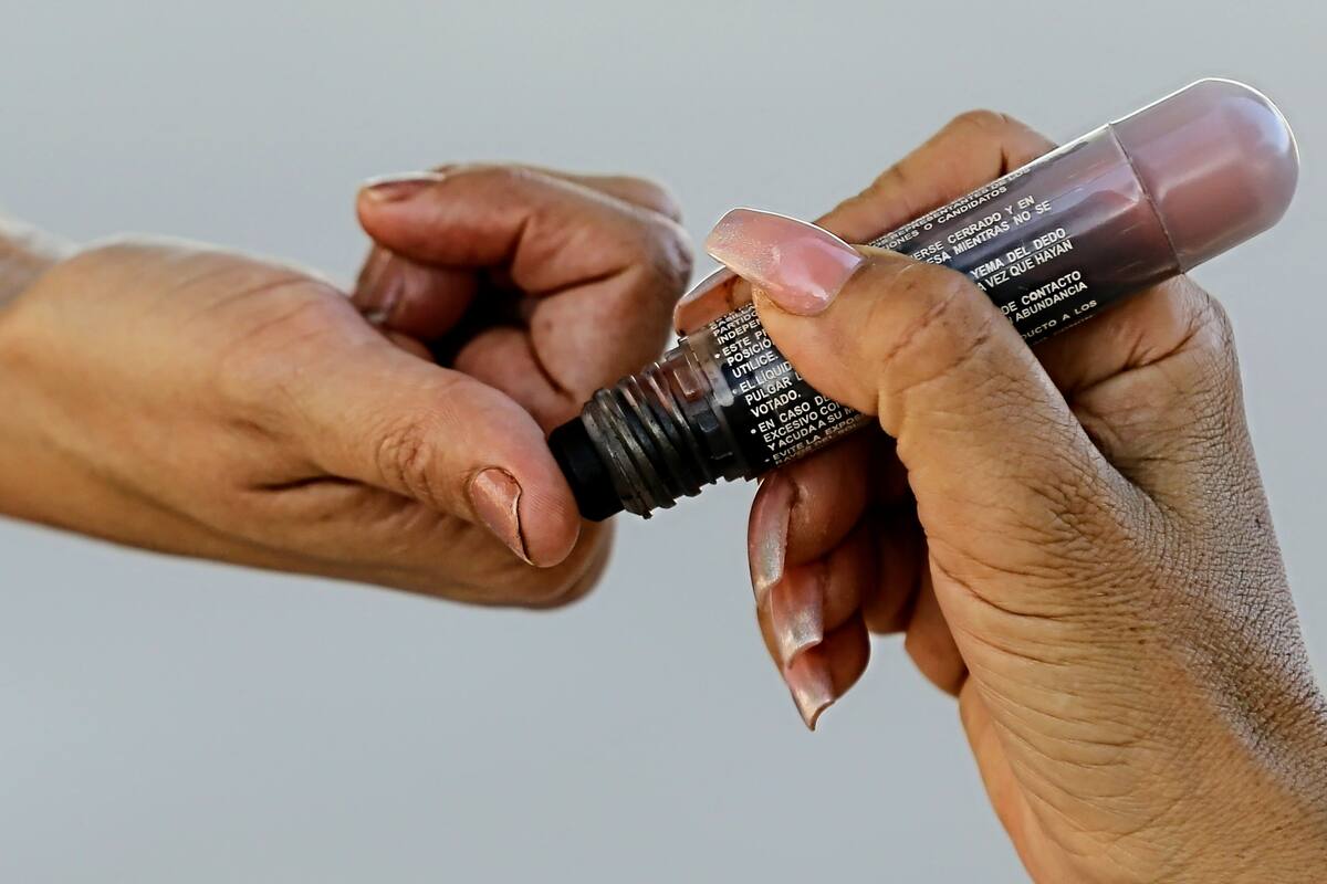 Funcionario de casilla marca el dedo pulgar con tinta para distinguir que el ciudadano ya votó. | Eleazar Escobar