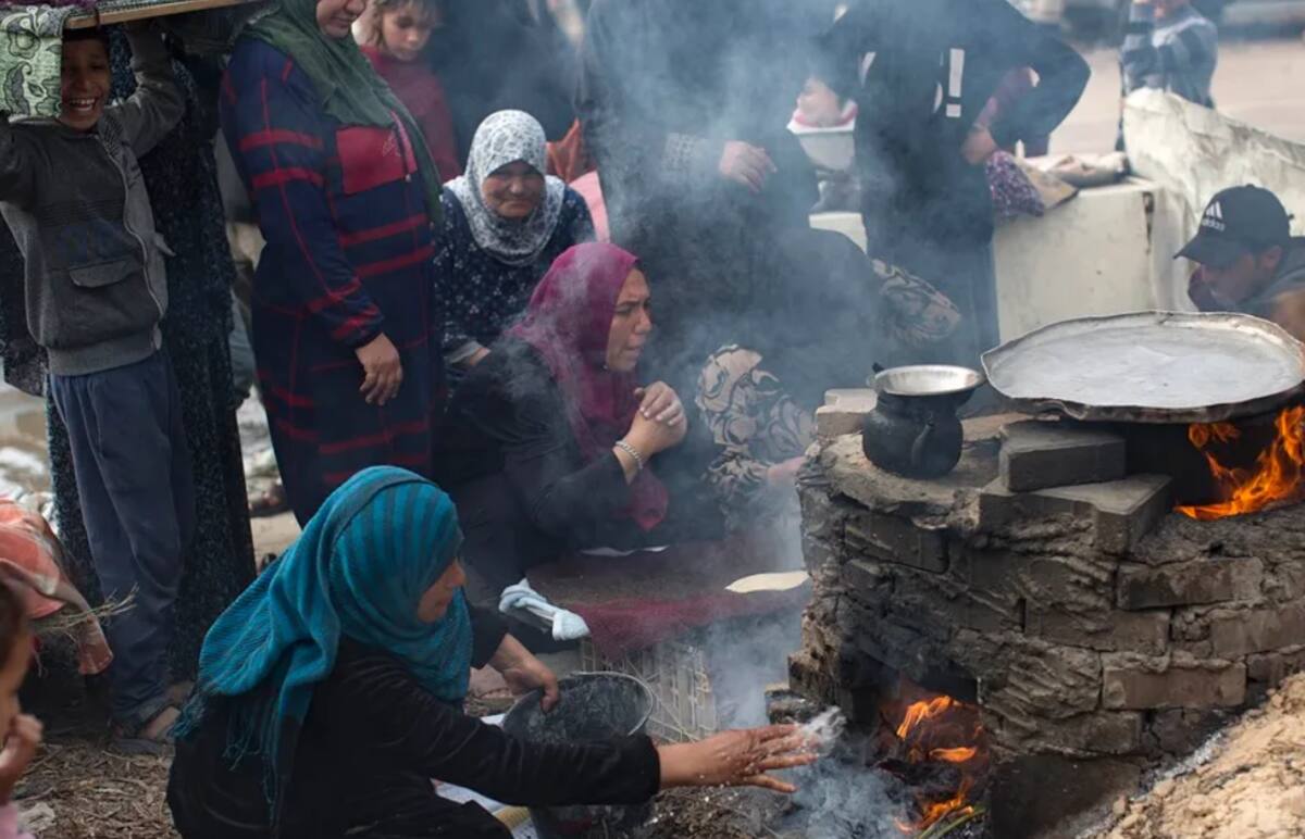 Familias palestinas desplazadas hacen pan en un horno de leña en un campo de refugiados en Rafah. /  EFE