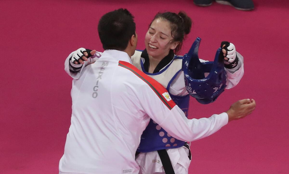 La mexicana Daniela Souza es felicitada por su entrenador, tras obtener el oro en el taekwondo, dentro de la categoría de 49 kilogramos, en los Juegos Panamericanos de Lima, el sábado 27 de julio de 2019 (AP Foto/Fernando Llano)