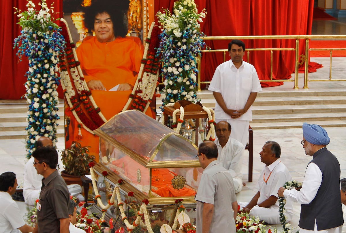 Indian Prime Minister Manmohan Singh, right, offers floral tribute to the body of Hindu holy man Sathya Sai Baba during a public viewing at the Prasanthi Nilayam Ashram in Puttaparti, India, on the eve of his funeral Tuesday, April 26, 2011. The 84-year-old guru's Sunday death triggered an outpouring of grief from followers who included Indian politicians, movie stars, athletes and industrialists. (AP Photo/Aijaz Rahi)