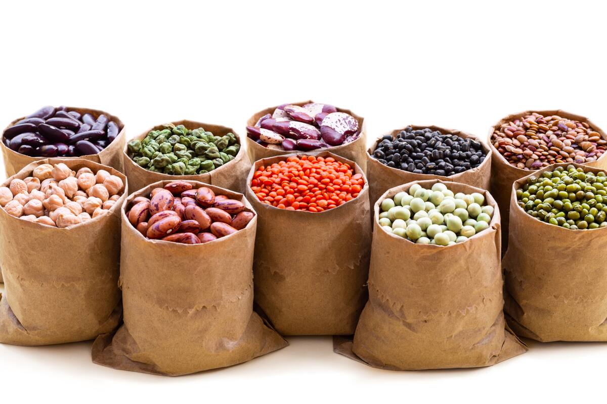 Various assortment set of indian legumes in paper sack bags isolated on white background with copyspace. Vegetable protein, vegan food, healthy eating concept, design.