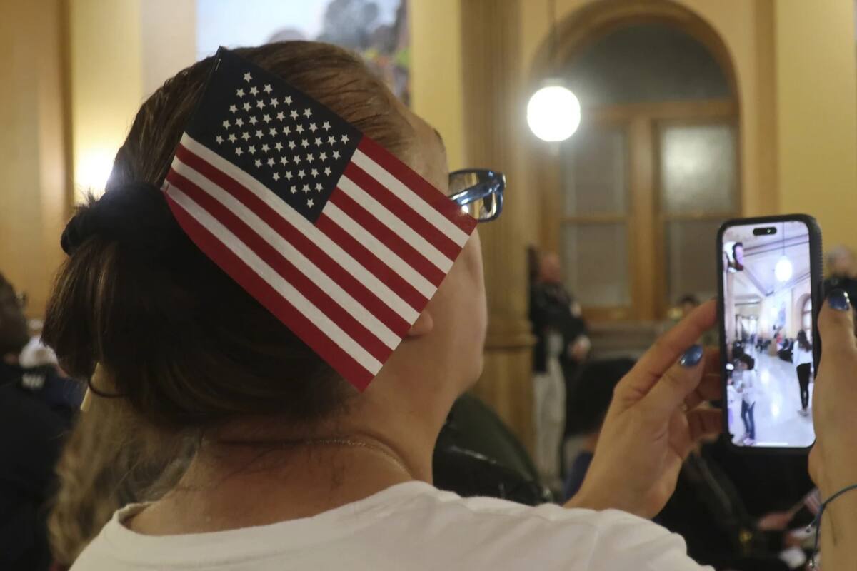 Una mujer graba la ceremonia donde 30 migrantes reciben la ciudadanía estadounidense el 27 de enero del 2025. | Crédito: AP