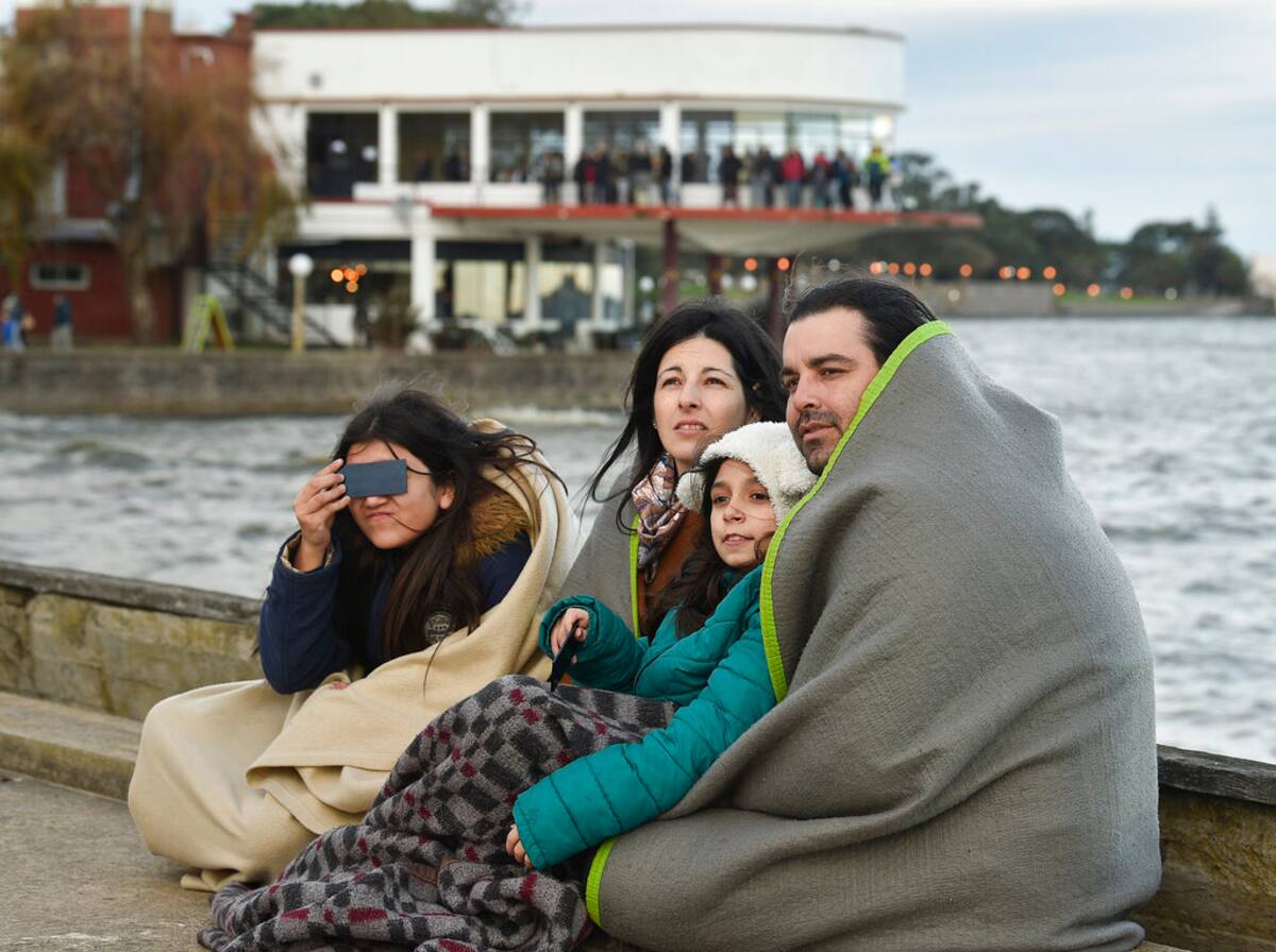 Una familia se cubre con mantas mientras observa un eclipse solar total en Chascomús, Argentina, el martes 2 de julio de 2019. (AP Foto/Gustavo Garello)