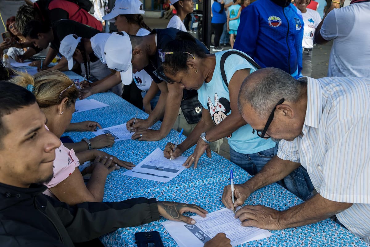 Personas participan en la recolección de firmas en apoyo a sus compatriotas migrantes deportados desde Estados Unidos a El Salvador este viernes, en Caracas (Venezuela).