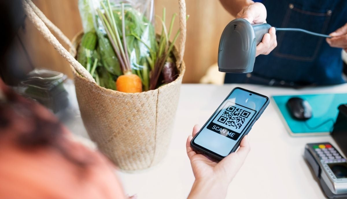 Un cliente presenta el código QR en la pantalla de su teléfono celular para realizar un pago electrónico en el mostrador de un comercio. | Magnific