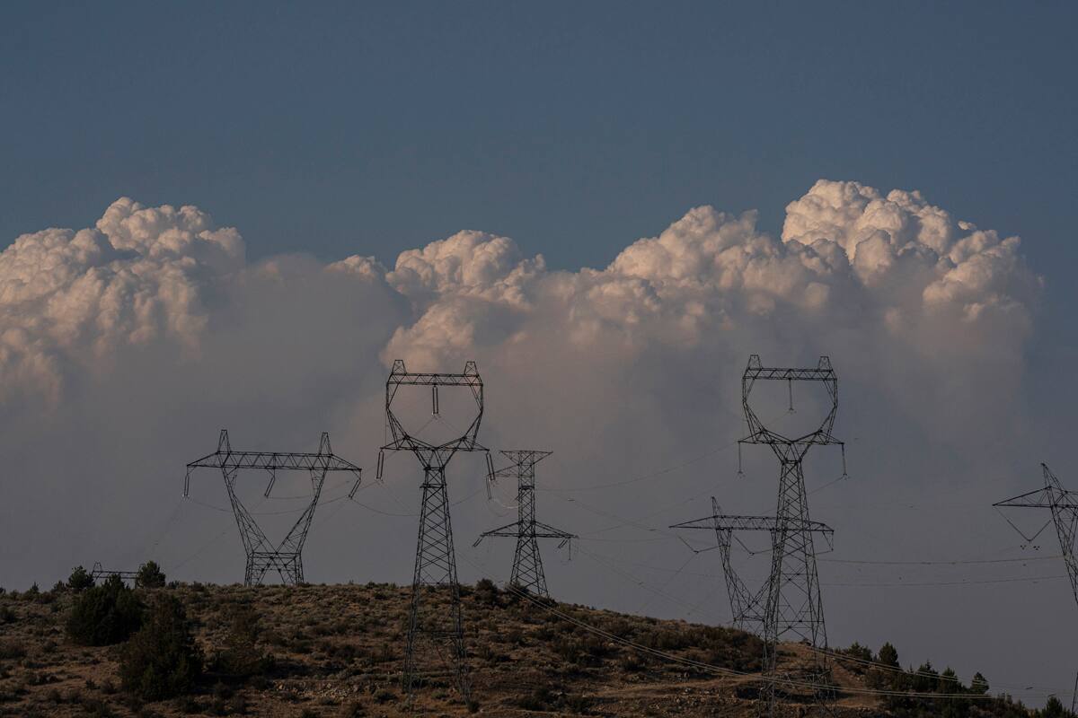 Nubes de humo causadas por el incendio forestal Bootleg Fire se alzan sobre líneas del tendido eléctrico el 12 de julio del 2021 cerca de Klamath Falls, Oregon. (AP Foto/Nathan Howard)