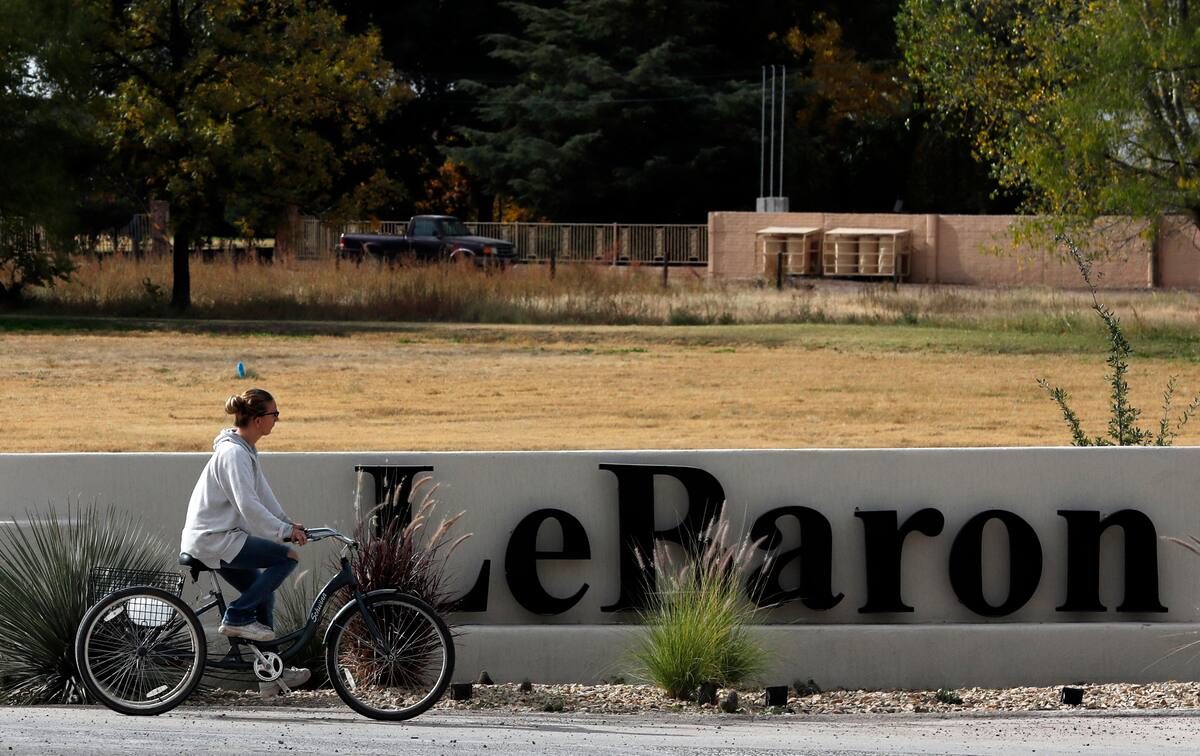 Una mujer pasa en bicicleta por delante del cartel de Colonia LeBarón, una comunidad establecida por miembros de la familia extendida LeBarón en el estado de Chihuahua, en el norte de México, el 6 de noviembre de 2019. (AP Foto/Marco Ugarte)