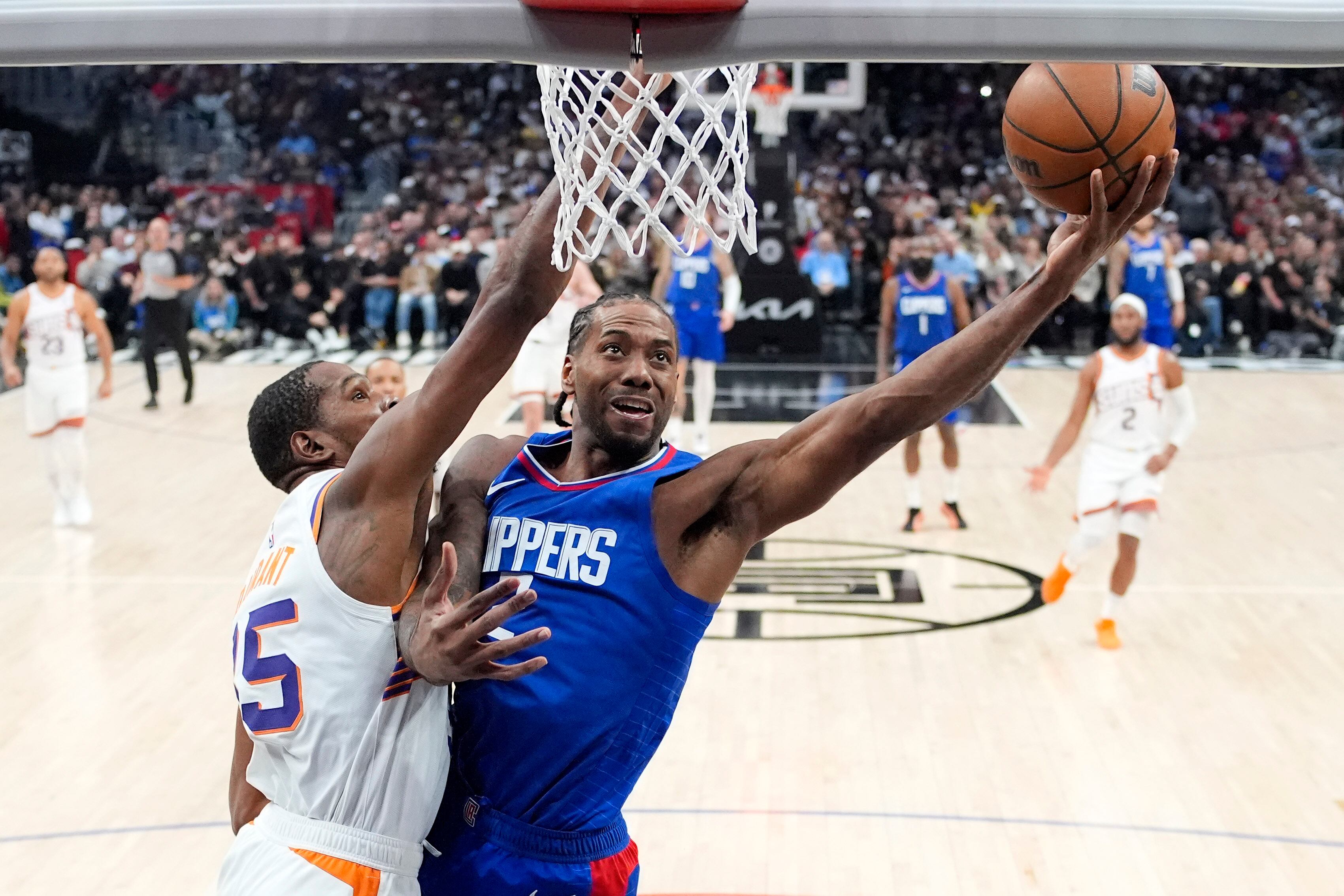 Kawhi Leonard (derecha) de los Clippers de Los Ángeles dispara al aro ante Kevin Durant de los Suns de Phoenix, el lunes 8 de enero de 2024. (AP Foto/Mark J. Terrill)