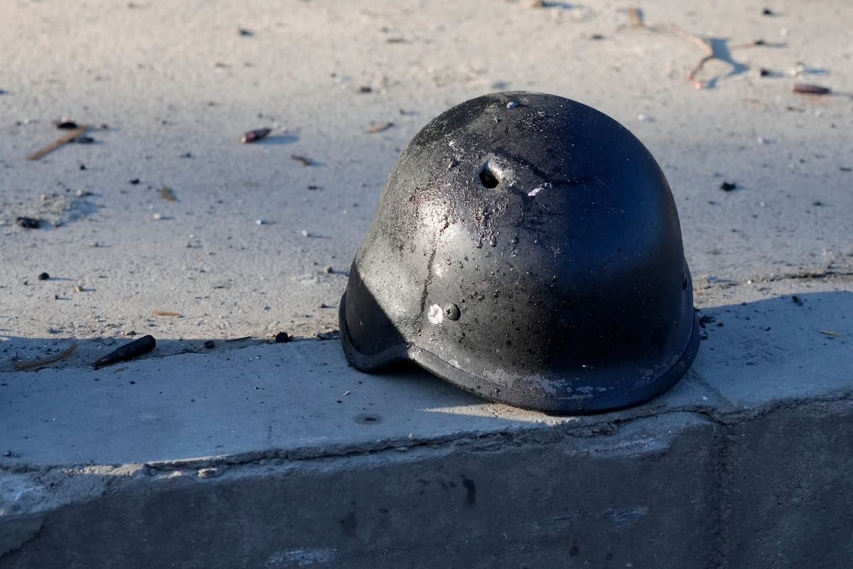 El casco de un soldado, con un agujero, cerca de los restos de camiones militares calcinados, en una calle de Kiev, Ucrania, el 26 de febrero de 2022. (AP Foto/Efrem Lukatsky)
