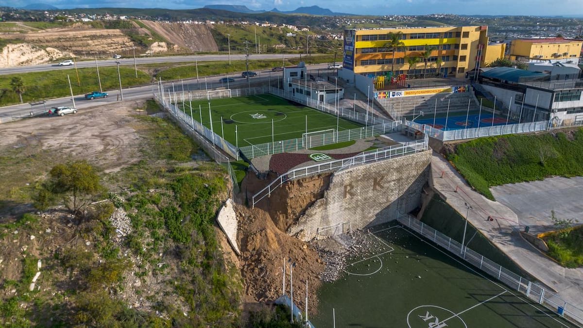 Un deslave de tierra provocado por las recientes lluvias ocasionó el colapso de una barda que dividía dos canchas deportivas del Instituto Kolbe, dejando un cúmulo de tierra, rocas y fragmentos de concreto. Foto: Border Zoom