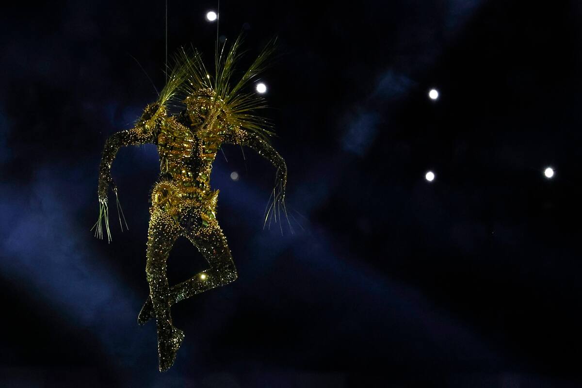El traje del "Viajero Dorado", diseñado por Kevin Germanier, se inspiró en el Disco de Oro de las sondas Voyager, representando un mensaje de la humanidad al espacio con elementos de ciencia ficción y valores olímpicos. Foto: EFE