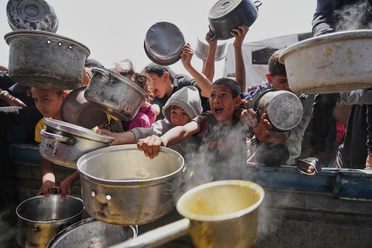 Un niño palestino intenta conseguir comida donada en una cocina comunitaria, el sábado 3 de mayo de 2025, en Jan Yunis, Franja de Gaza. (AP Foto/Abdel Kareem Hana)
