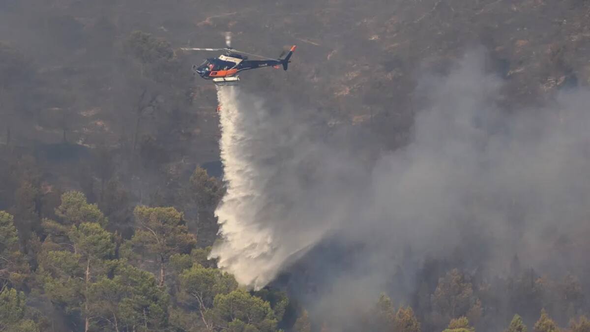 Un helicóptero de extinción de incendios arroja agua sobre un incendio forestal cerca de Correns. (AP)