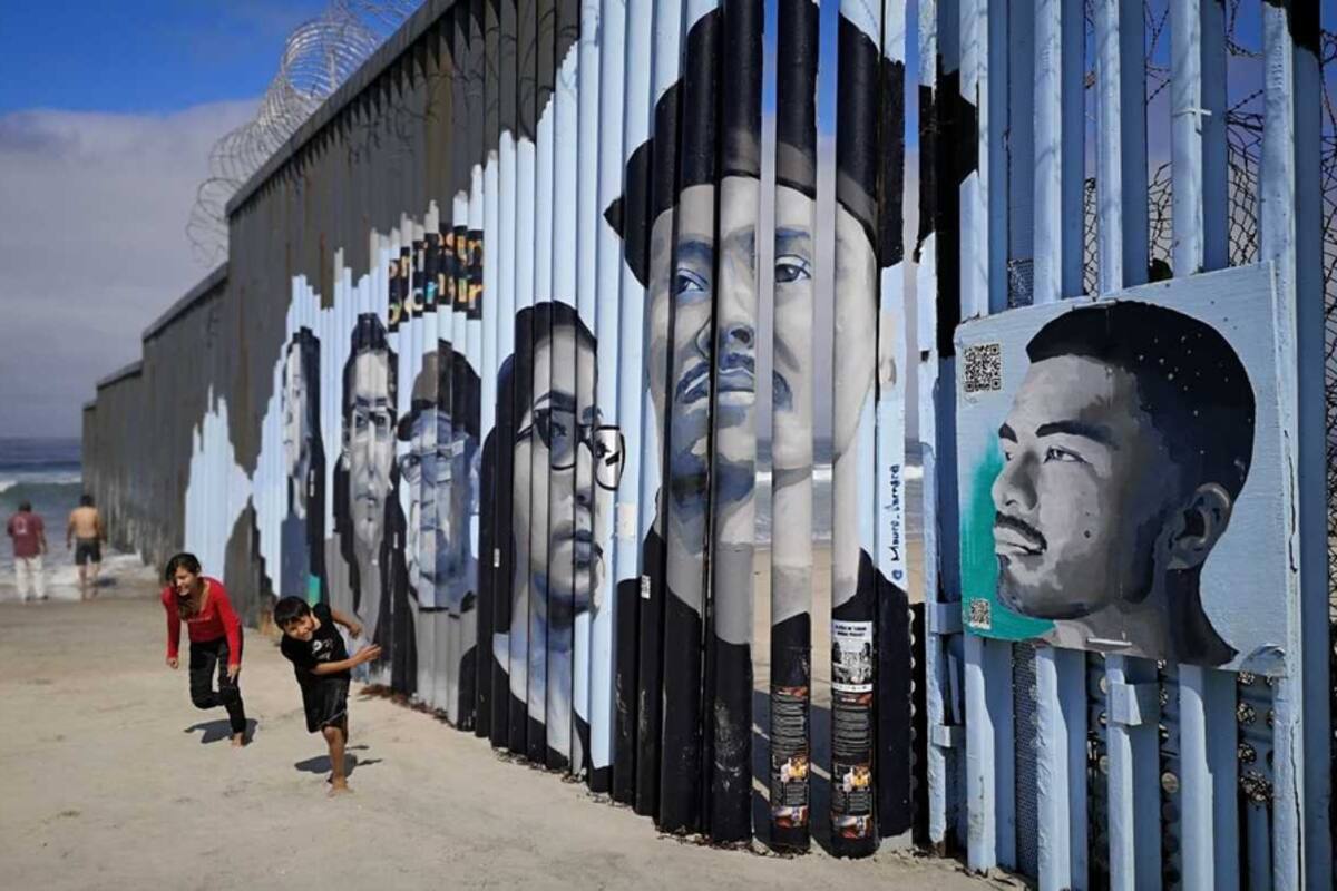 Rostros de migrantes son pintados sobre valla fronteriza