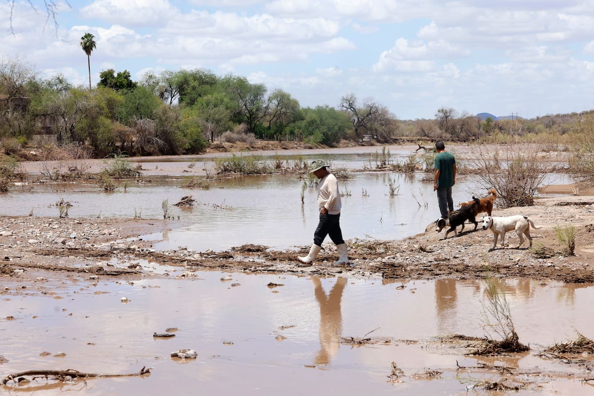 Habitantes del San José caminan entre las elevaciones de tierra para cruzar el río.